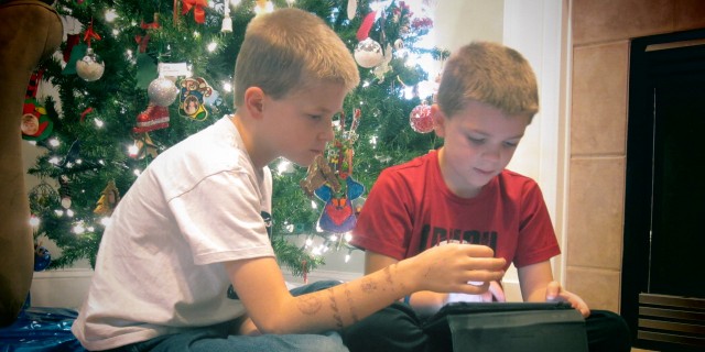 How Augmentative Communication (AAC) Can Help Holiday Voices Be Heard Children using a tablet by the Christmas tree.