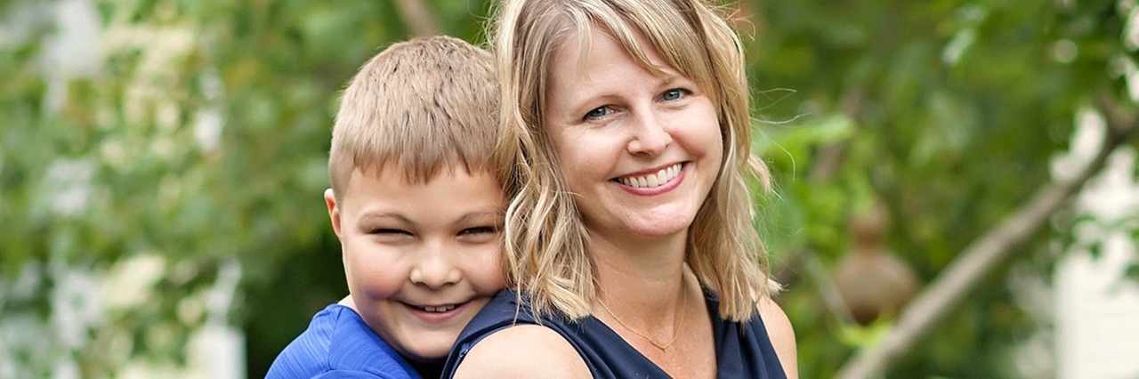Faces of Autism Book Shows Real Children on the Spectrum son hugging his mother from behind while posing outdoors