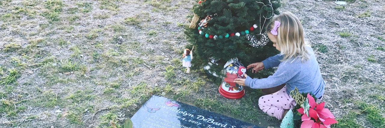 The author's daughter decorating her sister's Christmas tree at the cemetery