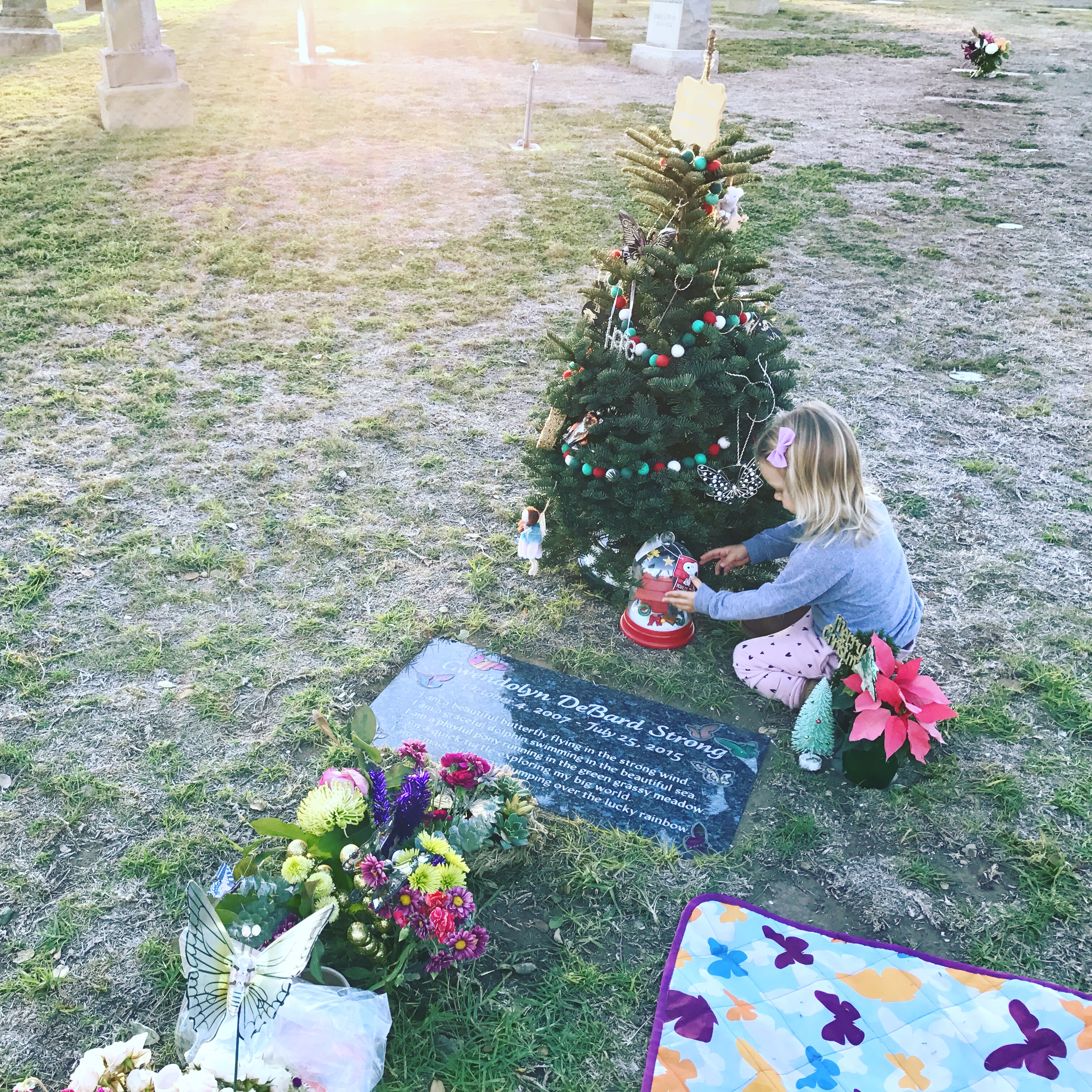 The author's daughter decorating her sister's Christmas tree at the cemetery