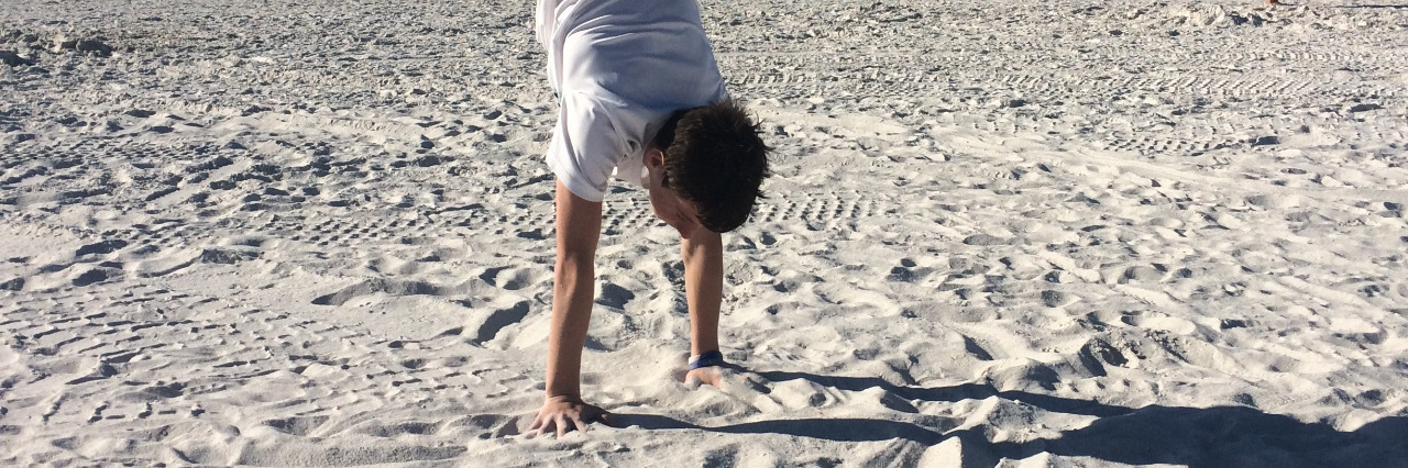 Erin's son doing gymnastics on the beach.