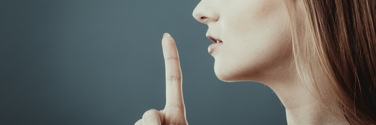 A Letter to People Who Question My Depression and Anxiety Closeup woman asking for silence or secrecy with finger on lips hush hand gesture, on blue background