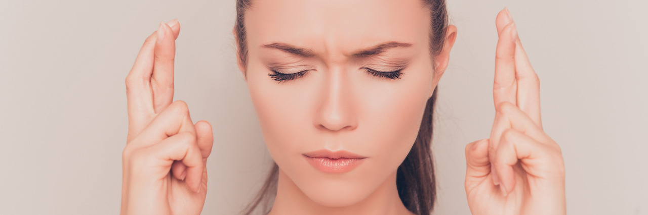 Letting Go of Needing a 'Cure' for My Dermatillomania A woman hoping for something with crossed fingers