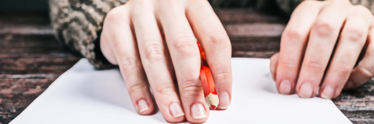 Writing to Cope With the Emotional Roller Coaster of Mental Illness A woman's hands, holding a pencil over a piece of paper as she begins write