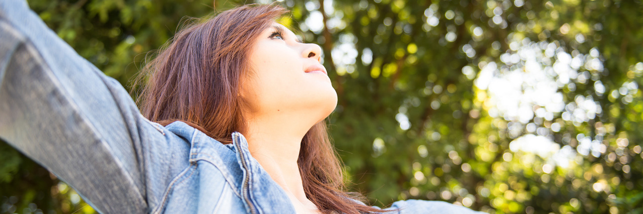 To the Person Making Comments About My Self-Harm Scars A young woman outdoors with her arms outstretched