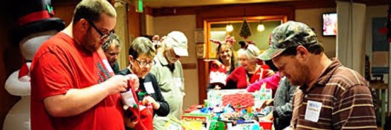 NAMI Shelby County Gives Christmas Gifts to Those With Mental Illness Three men looking at gifts on a table.