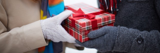 Image of gloved hand of guy giving his girlfriend Christmas present