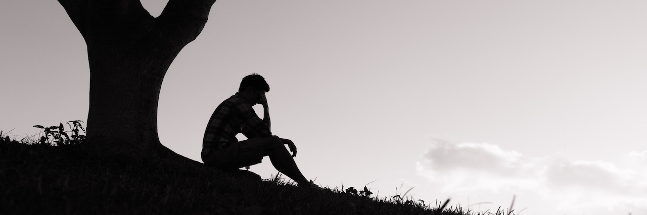 When Depression Makes Life Seem Meaningless Sad young men sitting under tree in the park.