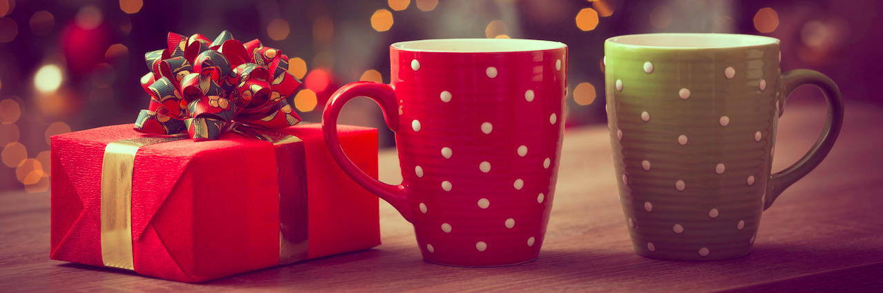 7 Gift Ideas for Someone With Schizophrenia Nicely wrapped gift box and two cups of hot coffee set on the coffee table with the decorated Christmas tree in the background