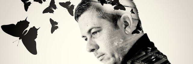 Single man with an industrial background double exposure background on his body with flying butterflies emerging from his head. Black and white monochrome image.