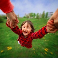 woman spinning a child while holding his hands