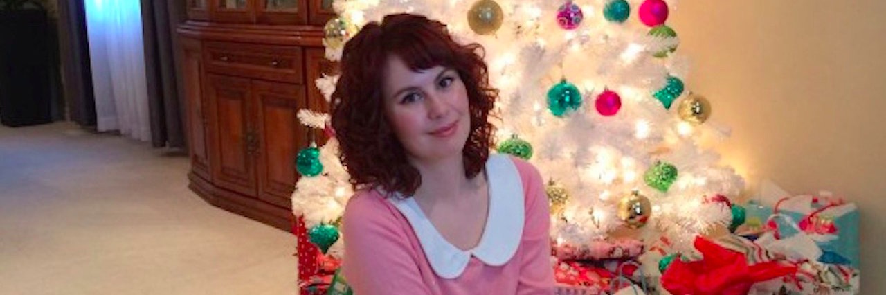 Tips for Getting Through the Holidays With a Chronic Illness woman with her dog in front of a Christmas tree