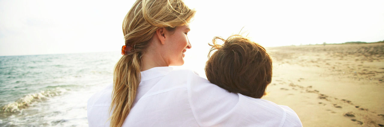 Mother and son (8-10) walking on beach, rear view, close-up