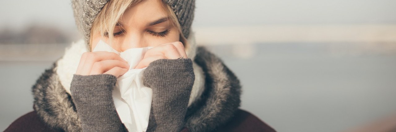 Woman With Charcot-Marie-Tooth Disease Worries During Cold Season young woman with a cold holding a tissue