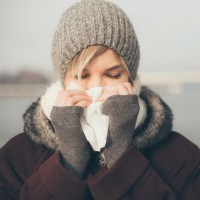 young woman with a cold holding a tissue