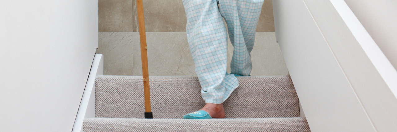 Woman walking down stairs with cane.