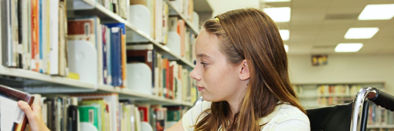Dealing With Bullies as a Wheelchair User A young teen girl in a wheelchair selecting a book at the library.