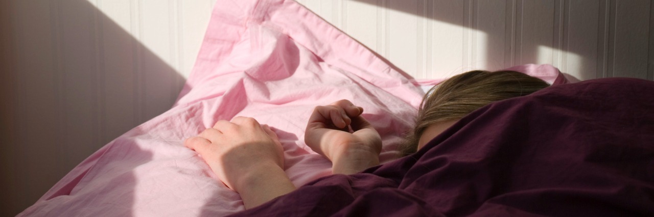 What Bipolar Disorder Mood Swings Can Look Like a woman under the covers with morning light streaming in through a window
