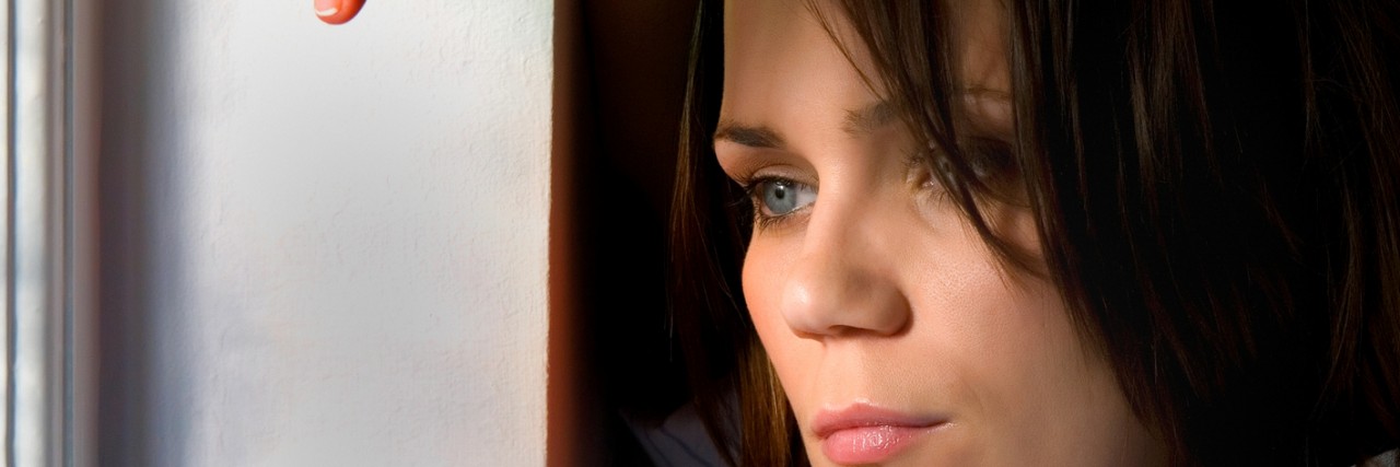 Midadult woman leans on window frame