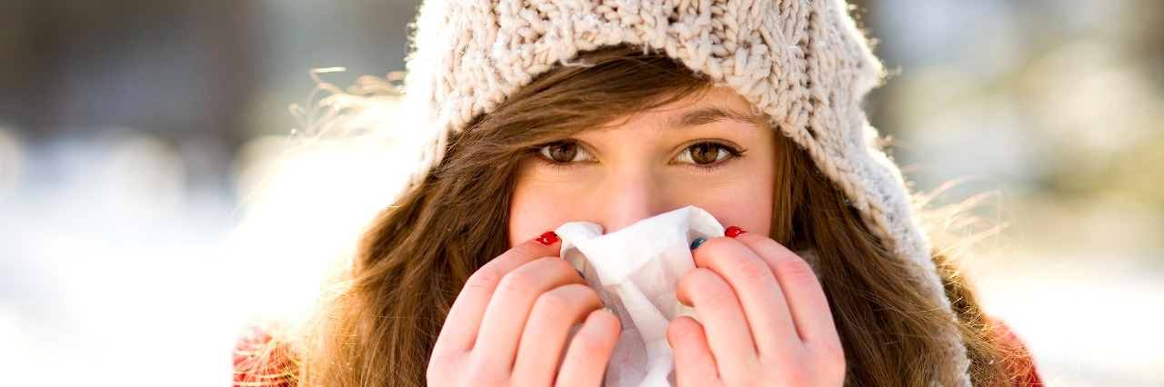 What Winter Months Are Like With Contamination OCD woman wearing a hat outdoors holding a tissue over her nose and mouth