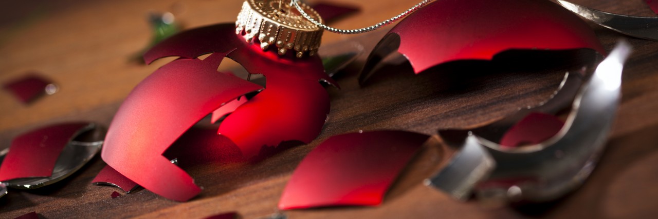 broken red christmas bauble and shards on wooden floor