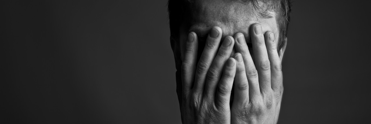 Feeling Shame When Giving or Receiving Gifts Black and white portrait of a man with his head held in his hands.