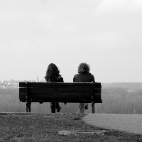 Black and white photo of two people sitting on a bench
