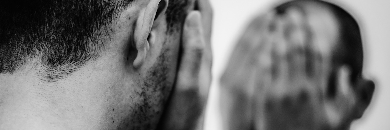 How Friends and Family Can Help Someone With Depression man looking in the mirror, holding his face in his hands