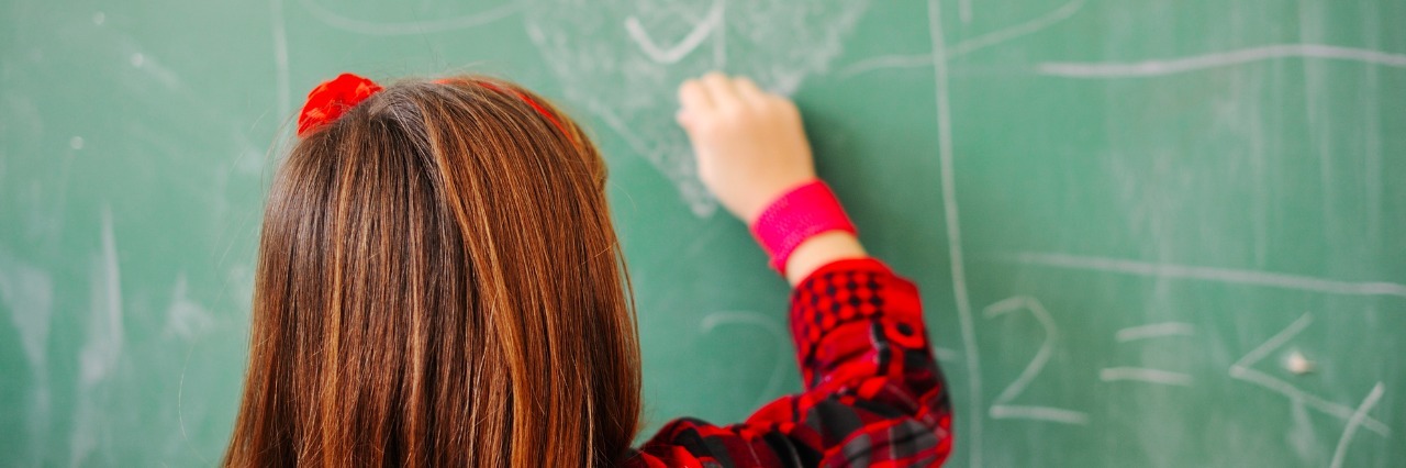 How Parents and Educators Can Support Children With Special Needs a young schoolgirl drawing a heart on a chalkboard