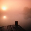 a dock looking over a misty lake at sunrise