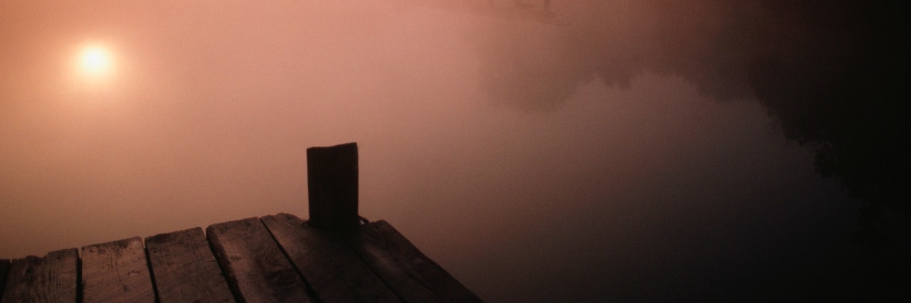 a dock looking over a misty lake at sunrise