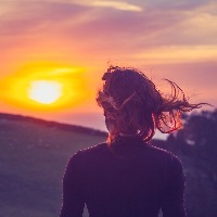 young woman admiring the sunset over fields