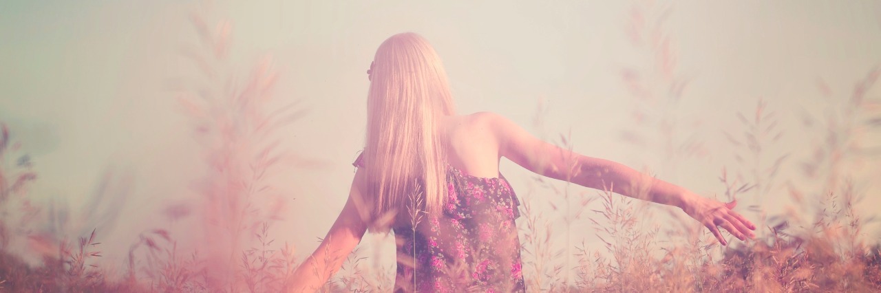 girl walking through field of long grass