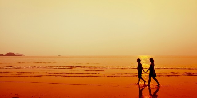 silhouette of couple walking on the beach holding hands