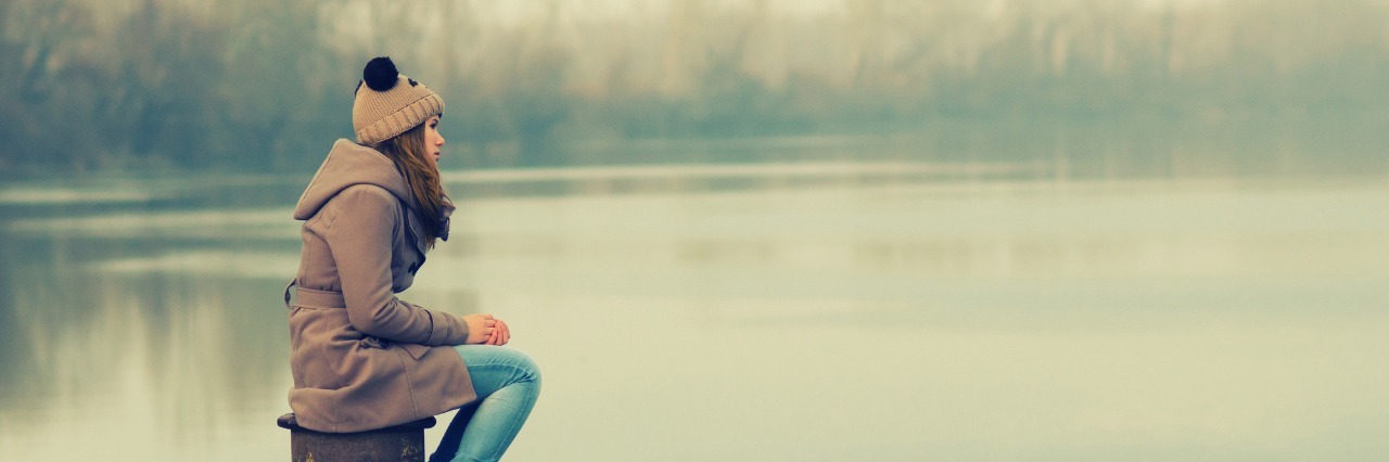 girl sitting on a dock during a gloomy winter day