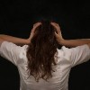 rear view of woman holding her head on black background