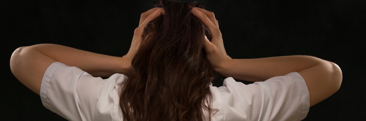 When One Condition Takes The Limelight, The Others Don't Go Away rear view of woman holding her head on black background