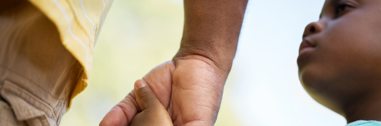 Child holding adult's hand.