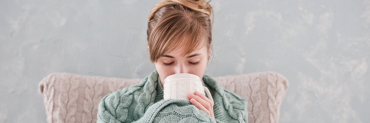 Chronic Illness: How to Prevent Sickness During the Holidays woman wrapped in blanket sipping tea