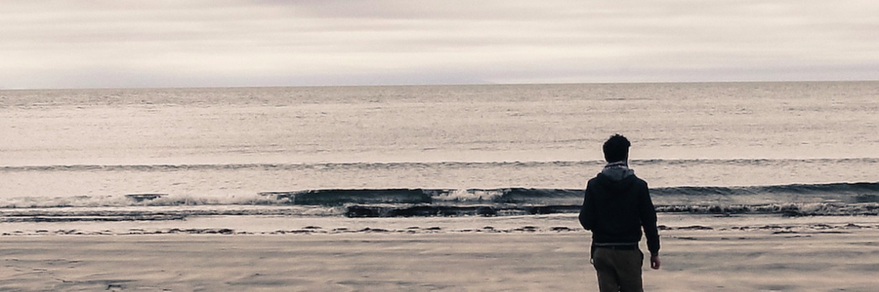 Snapshots of Grief: Reliving a Relationship in Photographs Picture of man from behind walking on a beach