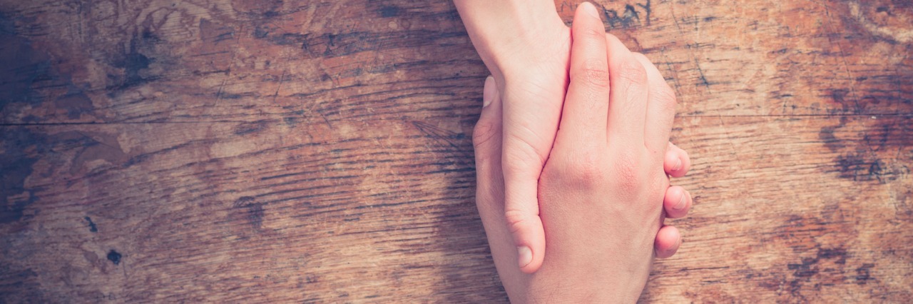 Deciding Who to Tell About My Colon Cancer Diagnosis Two people holding hands at a wooden table