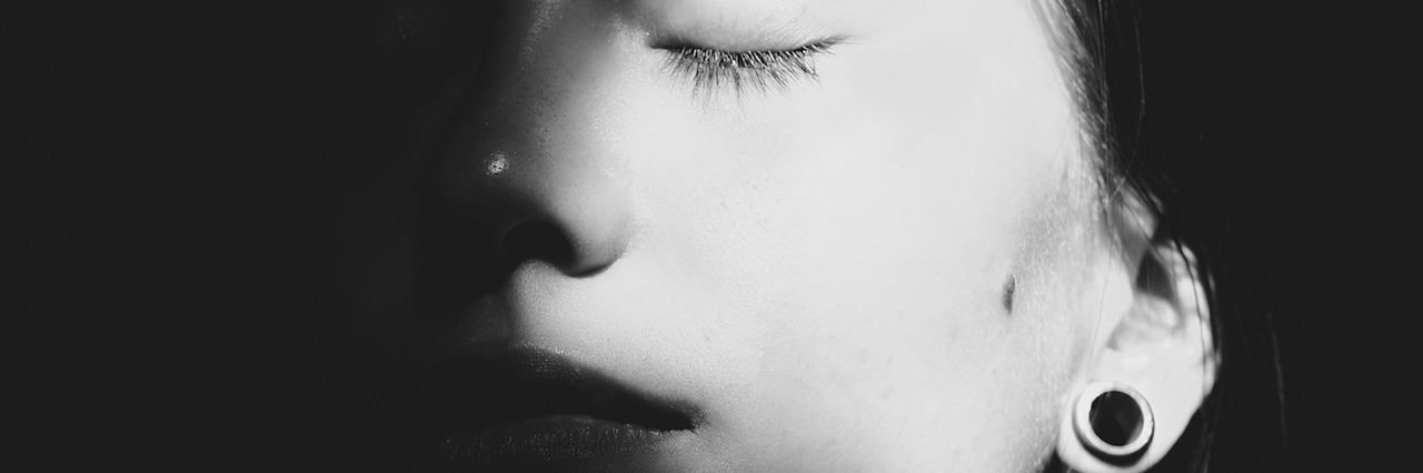 Chronic Depression: When You're Not Recovering woman closing her eyes in the shadows