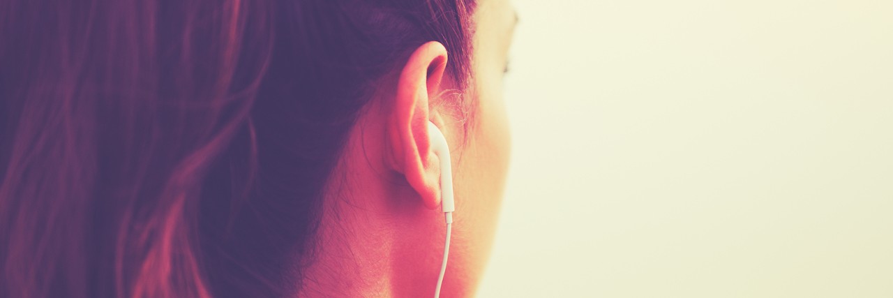 25 Songs to Listen to For Major Depressive Disorder back view of a woman's head with headphones in her ears
