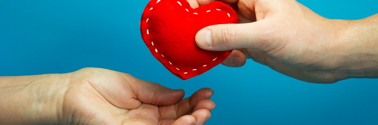 Man hand puting the red soft heart in woman hand