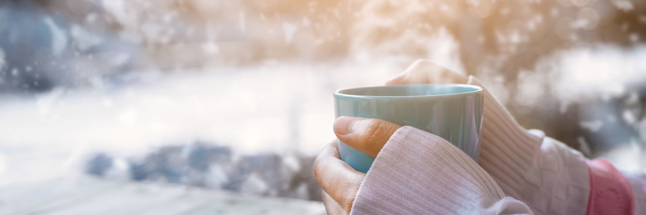 Side view of female hand holding hot cup of coffee in winter