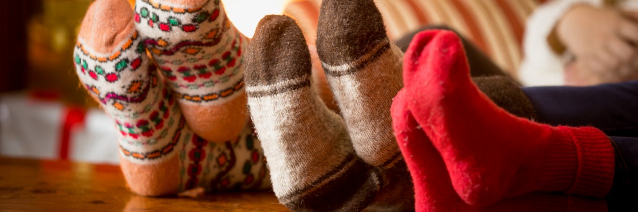 What My Daughter on the Autism Spectrum Has Taught Me About Christmas Closeup of family feet in wool socks at fireplace