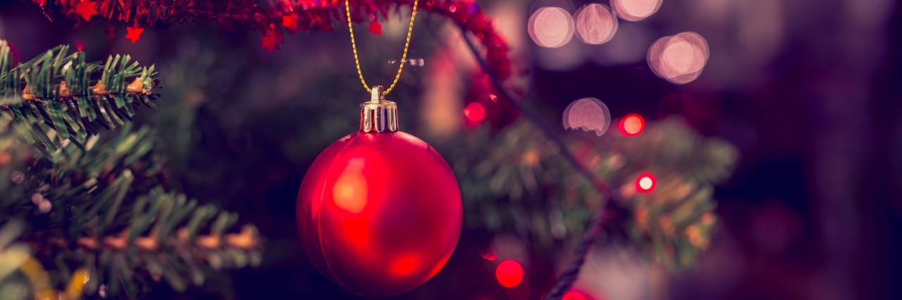 Celebrating Christmas Moments With My Autistic Daughter Closeup of red ornament hanging from Christmas tree