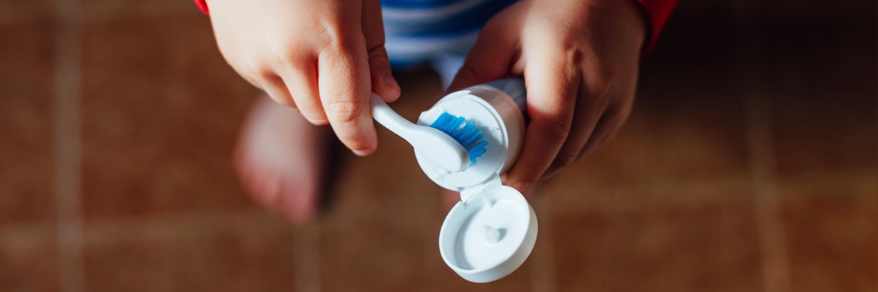 Tips for Helping Children With Sensory Issues Brush Their Teeth Boy putting toothpaste on toothbrush
