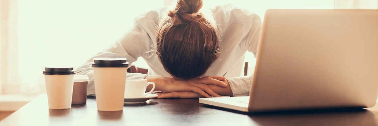 A woman with her head down on her desk