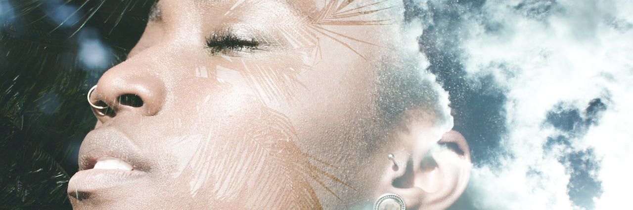 Double exposure portrait of african american woman combined with photograph of trees and sky